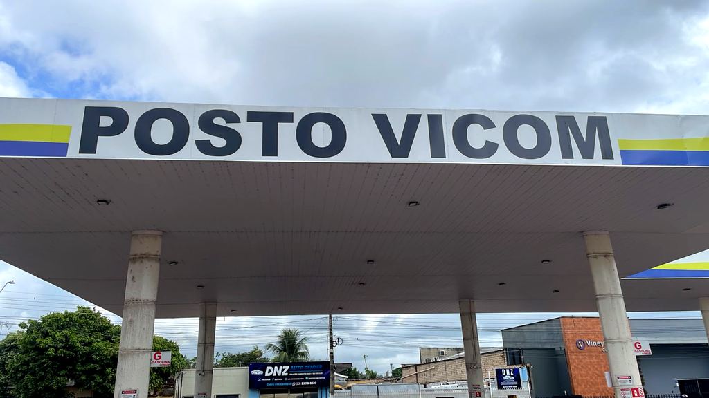 Letreiro POSTO VICOM em letras azuis sobre fundo branco, com faixa amarela e azul